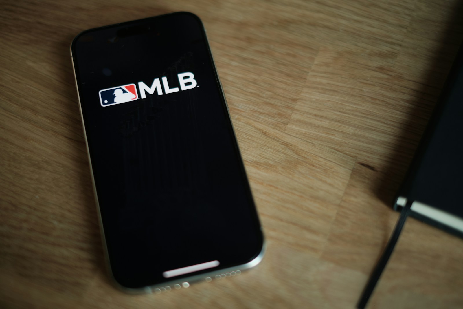 A black cell phone sitting on top of a wooden table